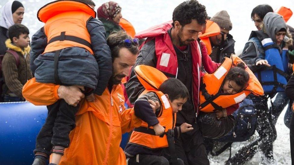 Refugees are helped from an inflatable boat after crossing the sea from Turkey to the Greek island of Lesbos. Photo: 9 March 2016