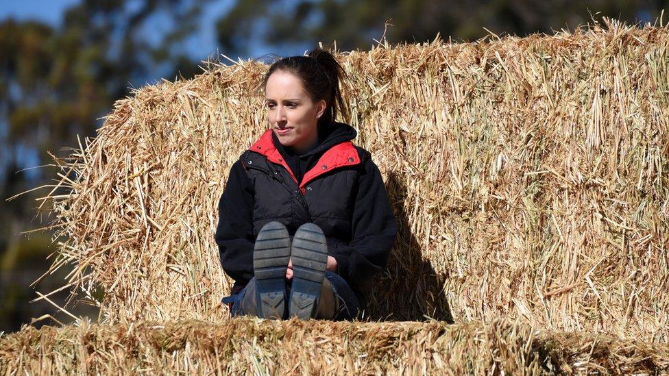 Jade Whatman sits on hay