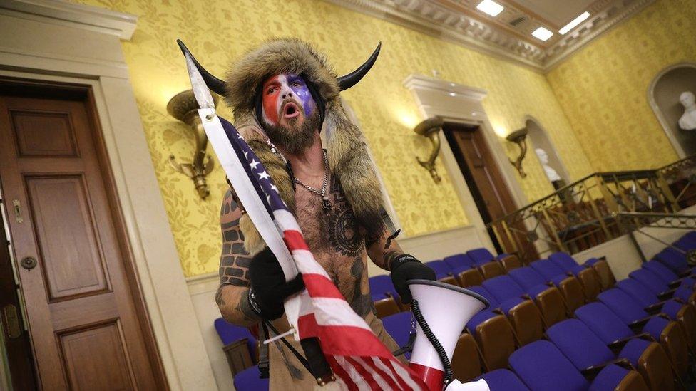 A man in horns and a fur hat, alleged to be Jake Angeli, pictured inside the Senate chamber