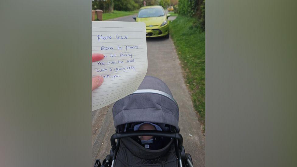 A pram with a baby, and a car blocking their way