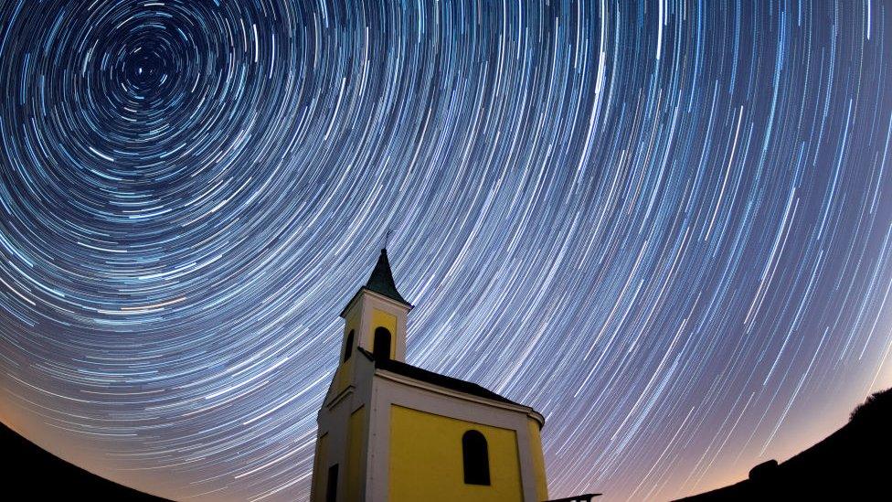 startrails form bright circles in the nights sky above a building