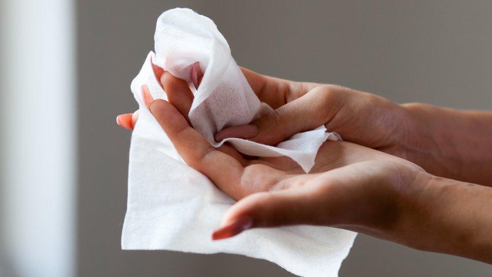 Woman wiping hands with wet wipe