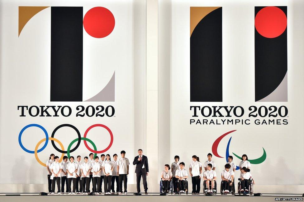 Hammer throw gold medallist Koji Murofushi (C), accompanied by young athletes, delivers a speech as the logo marks of the Tokyo 2020 Olympic (L) and Paralympic (R) Games are unveiled at the Tokyo city hall on 24 July 2015