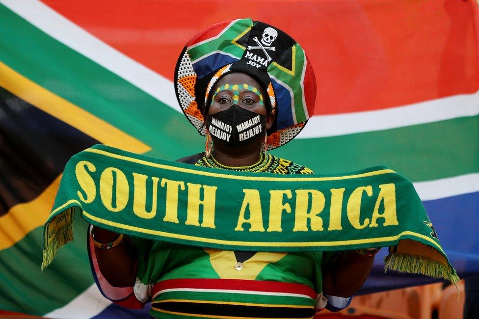 A woman wears South African football colours and the national flag.