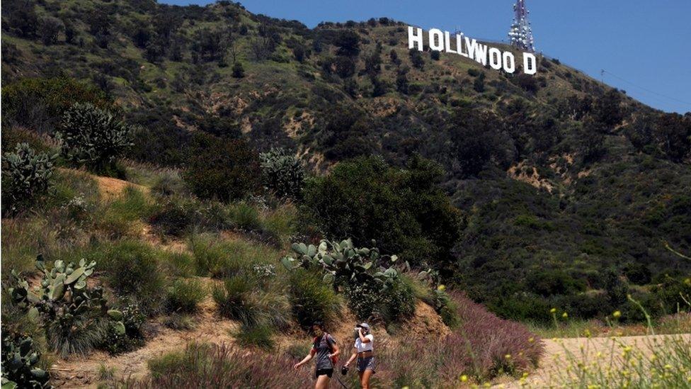 People hike beneath the Hollywood sign after a partial reopening of Los Angeles hiking trails during the outbreak of the coronavirus disease