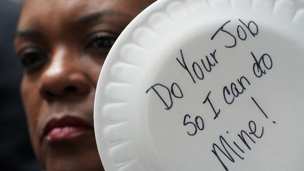 A federal employee holds up a sign made with plate during a protest in Washington, 23 January