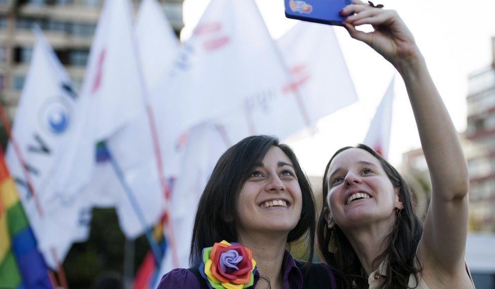 two women taking a selfie in front of celebration banners, January 2015