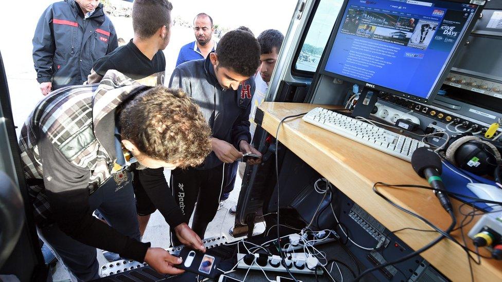 Migrants charge their mobile phones on the Austrian side of the border with Hungary - 19 September