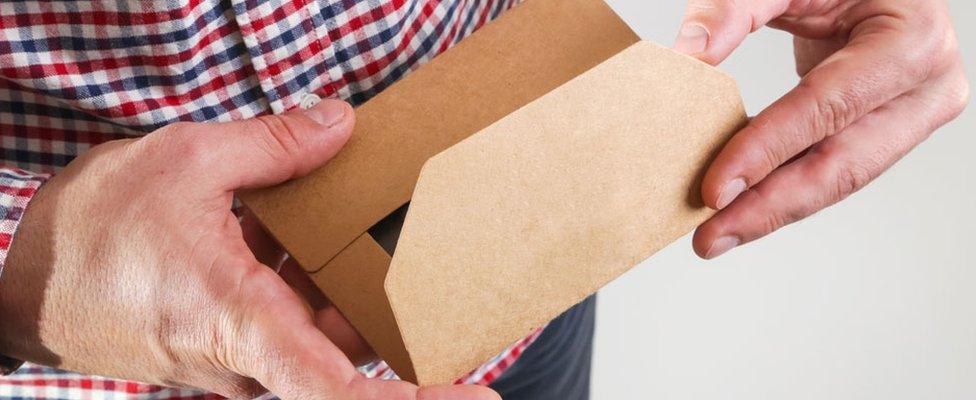 A stock picture of a man opening an envelope