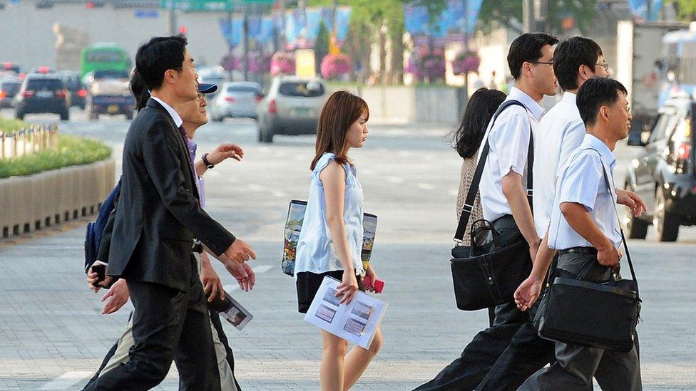 Koreans cross a road on their way to work.