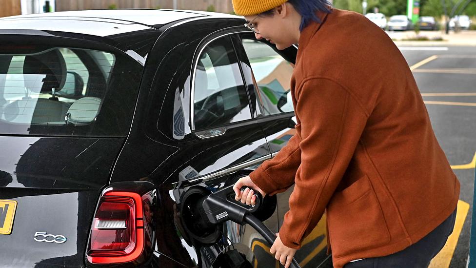 Woman plugging in electric car