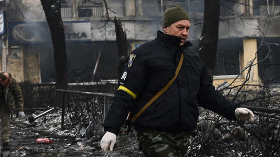 Police officers remove the body of a passerby killed in yesterday's airstrike that hit Kyiv's main television tower in Kyiv on 2 March 2022