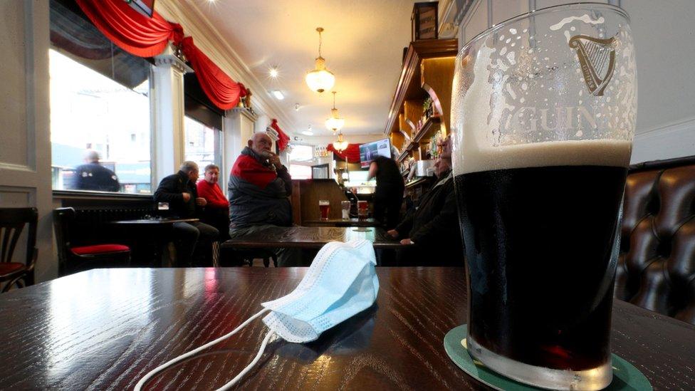 Pint of Guinness and face mask on pub table