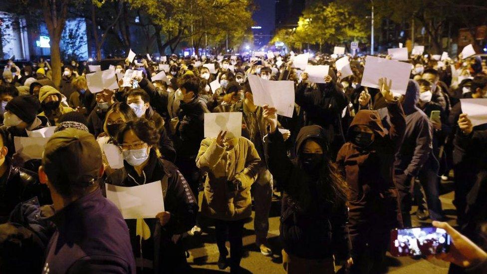 Protesters hold blank white pieces of paper during a protest triggered by a fire in Urumqi that killed 10 people in Beijing, China,