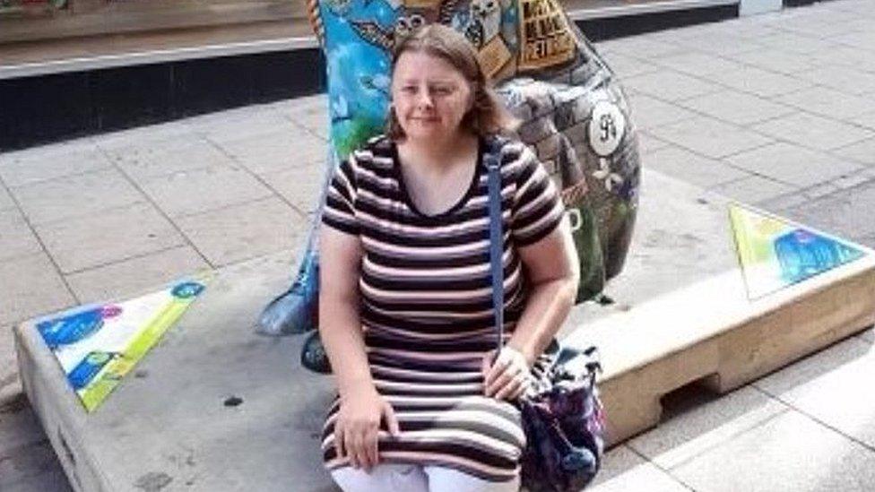 A woman sits next to a large painted model of the dog Gromit from Wallace and Gromit