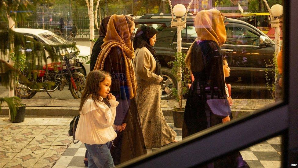 A group of women walk past a restaurant in Kabul