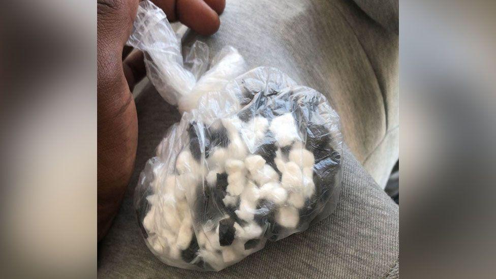 A plastic bag filled with white and black pills