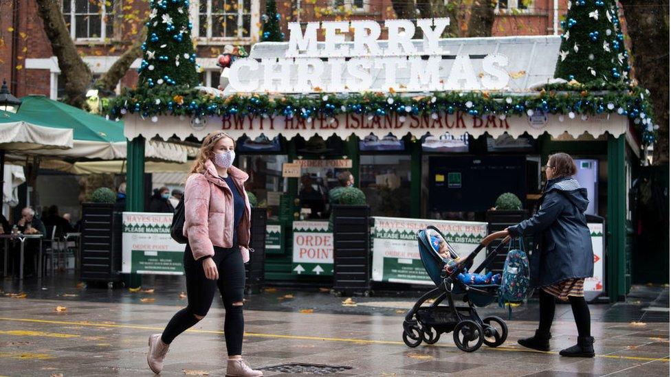 A woman with a face mask walking past Christmas decorations