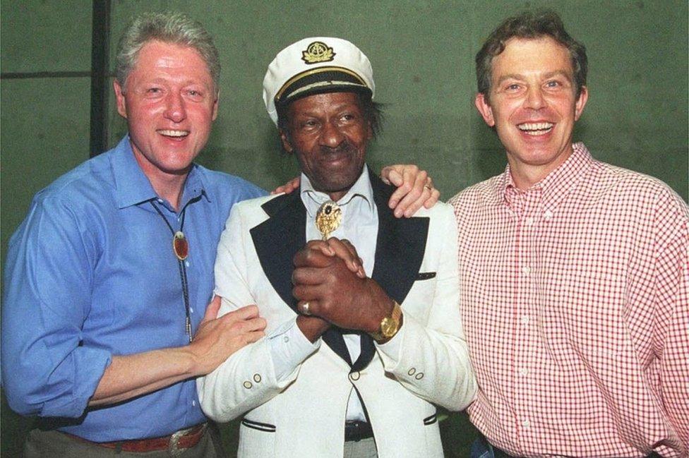 Then US President Bill Clinton (L) and British Prime Minister Tony Blair (R) pose for photographers with blues guitar legend Chuck Berry on 22 June, 1997