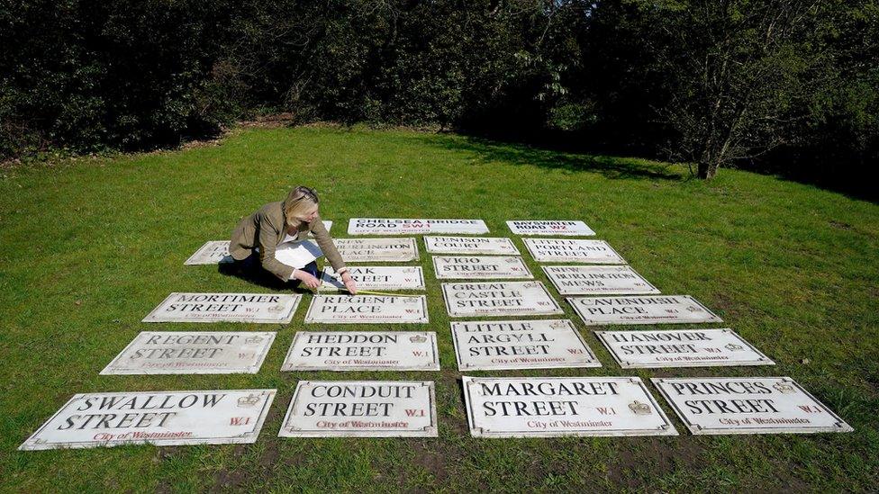 Woman sits with old London street signs