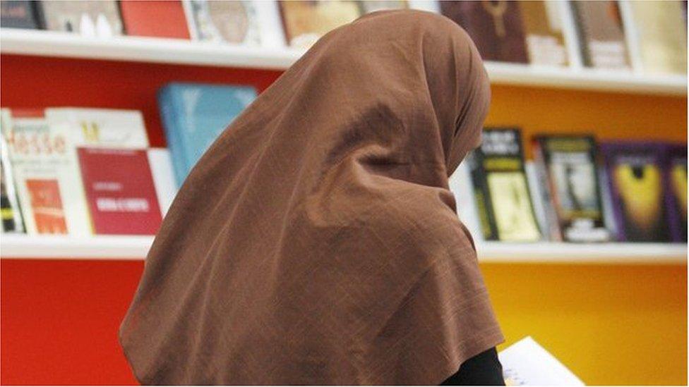 A veiled woman reads a book in front of shelves at the stand of Macedonia at the Leipzig Book Fair, 18 March 2010