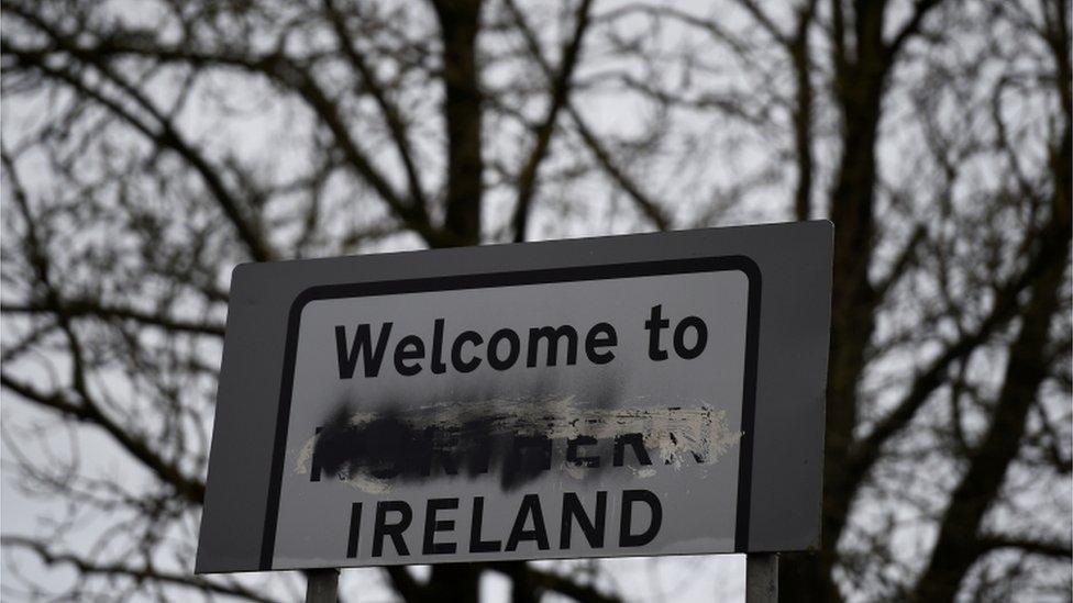 A defaced "Welcome to Northern Ireland" sign stands on the border in Middletown, Northern Ireland