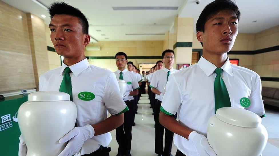 Attendants carry biodegradable urns at a cemetery in Tianjin, northern China, for a collective eco-burial on 20 July 2010.