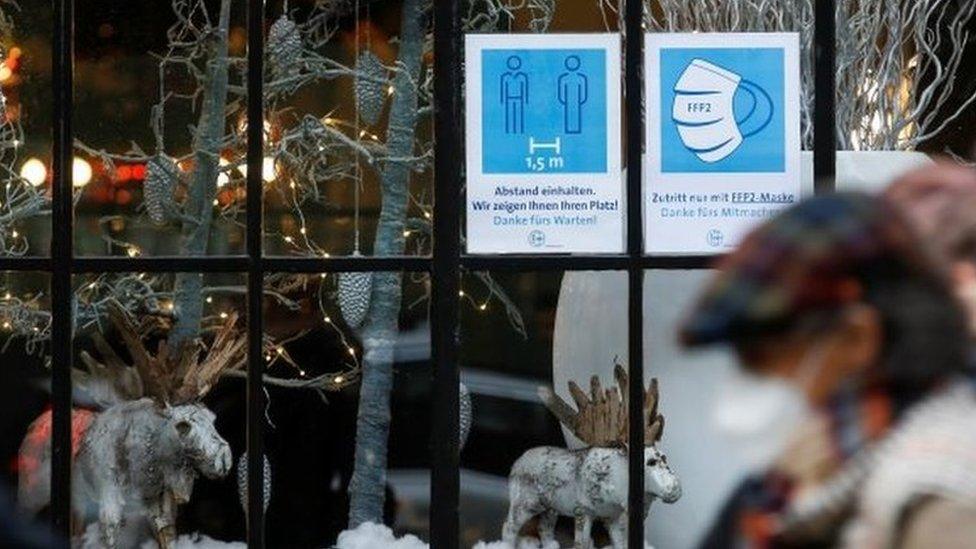 People pass by a restaurant window displaying coronavirus disease (COVID-19) safety measures,