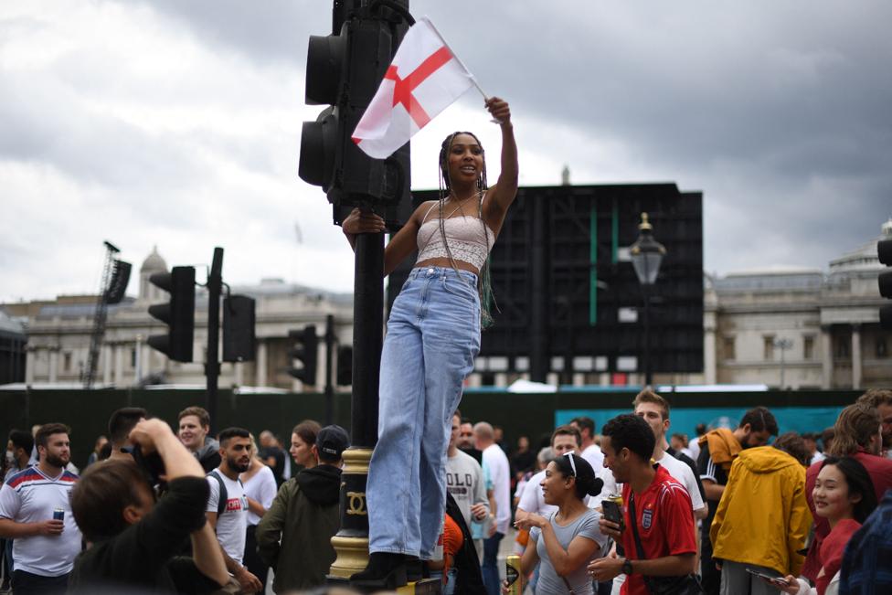 A woman waves an England flag as England fans gather in central London ahead of the UEFA EURO 2020 final football match between England and Italy on July 11, 2021.