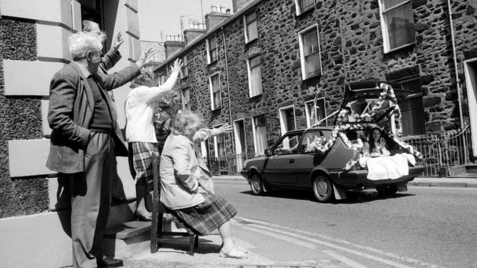 A carnival queen being driven around in the open boot of a car in Pwllheli