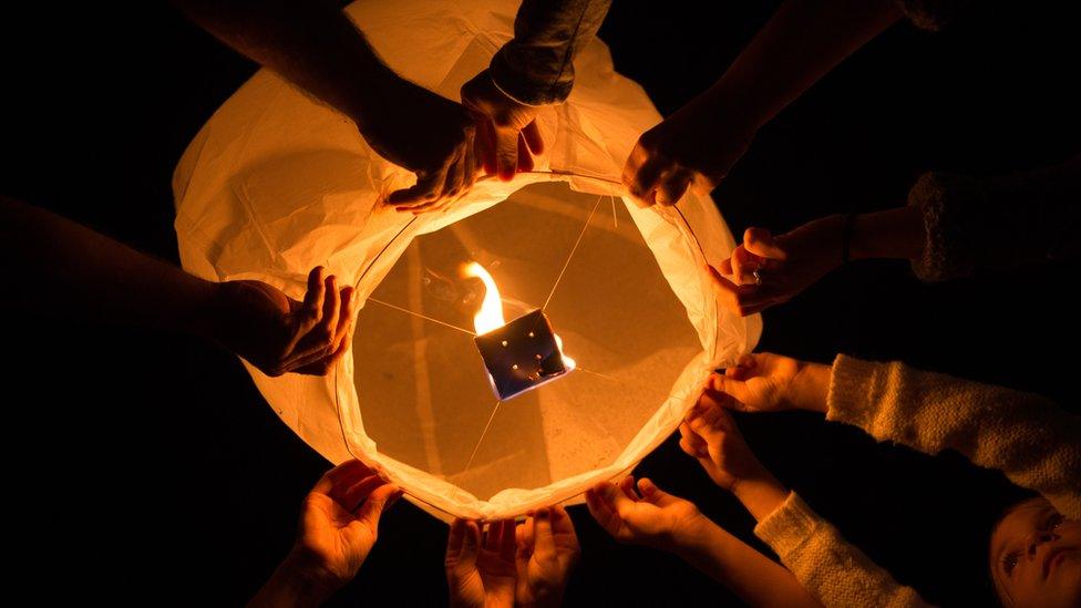 People lighting a lantern