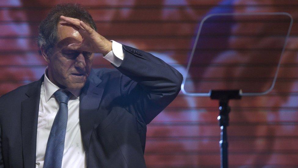 Daniel Scioli scratching his head and looking at the floor