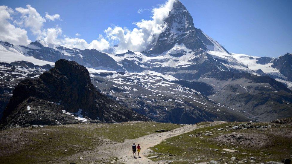 A couple of tourists walk on a trail below the Matterhorn mountain in Zermatt on 30 June 2015