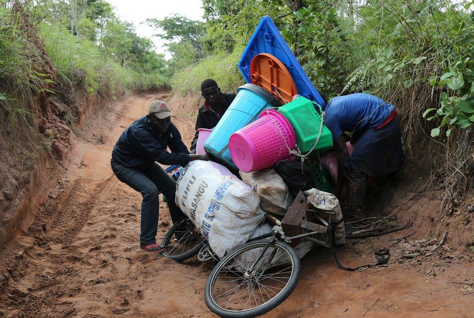 Congolese migrants expelled from Angola attempt to push a rented bicycle to transport their belongings along the dirt road to Tshikapa, Kasai province near the border with Angola in the Democratic Republic of the Congo, October 12, 2018.