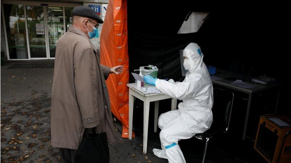 A health worker in protective suit gives a document to man, amid the coronavirus disease (COVID-19) outbreak, at a test centre in front of a hospital in Warsaw, Poland on 27 October 2020.