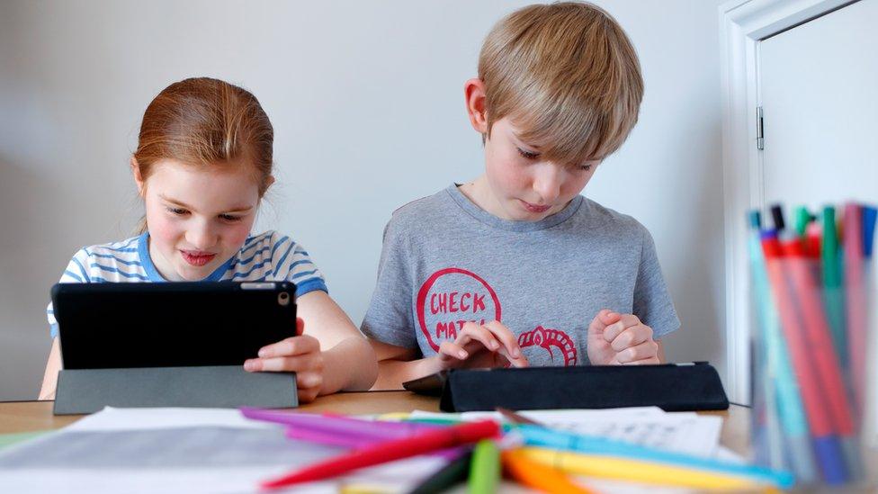 Two UK children doing school work at home