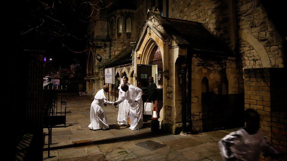 Worshippers greet following a night-time Christmas Eve service at the Celestial Church of Christ in Elephant and Castle