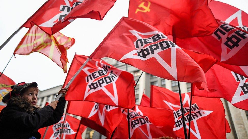 A boy in Moscow waves a communist flag during a rally to mark the 100th anniversary of the October 1917 revolution