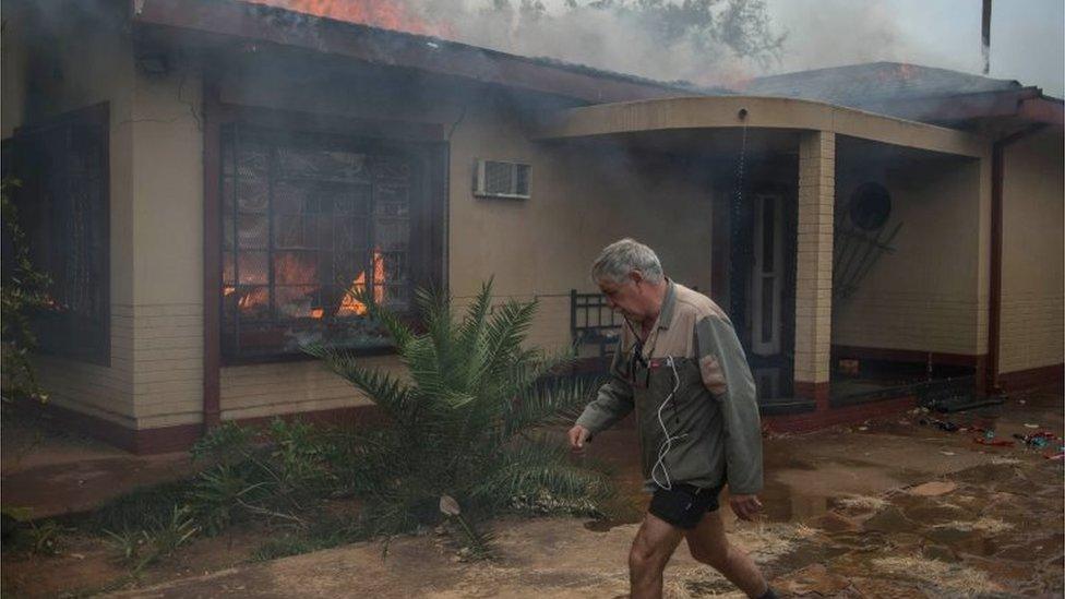 A man walks past a burning house in Coligny that was reportedly set on fire by protesters during clashes that erupted after a court bailed two men accused of killing a boy on May 8, 2017