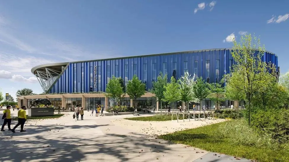 A computer generated image of the planned Oxford United stadium, with a blue outside and a small collection of trees to the right of it 