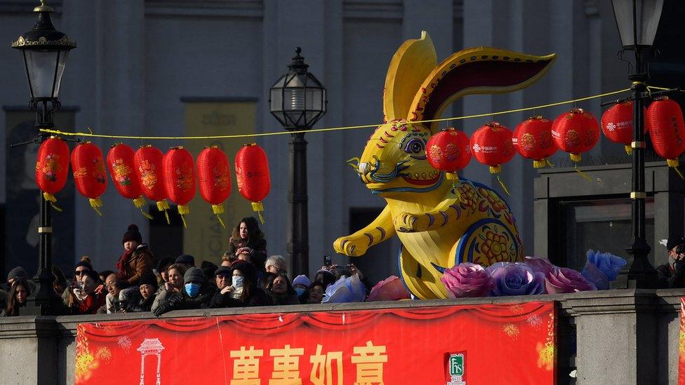 People stand by a large rabbit farm as they watch a parade during celebrations on the first day of the Lunar New Year in London