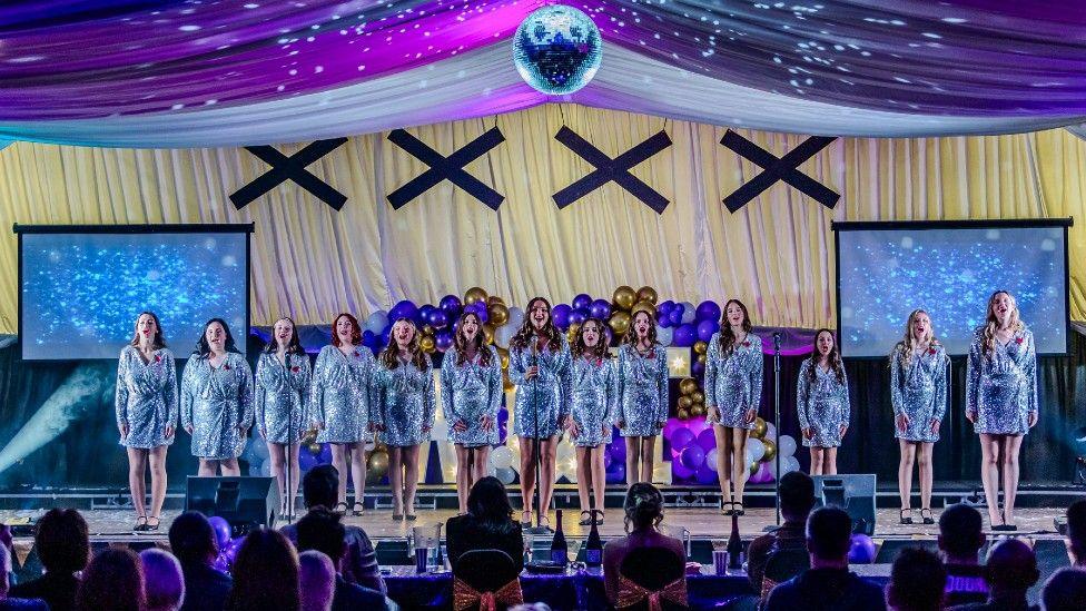 A stage performance during Worksop's Got Talent, feature a choir of women in silver glitter dresses