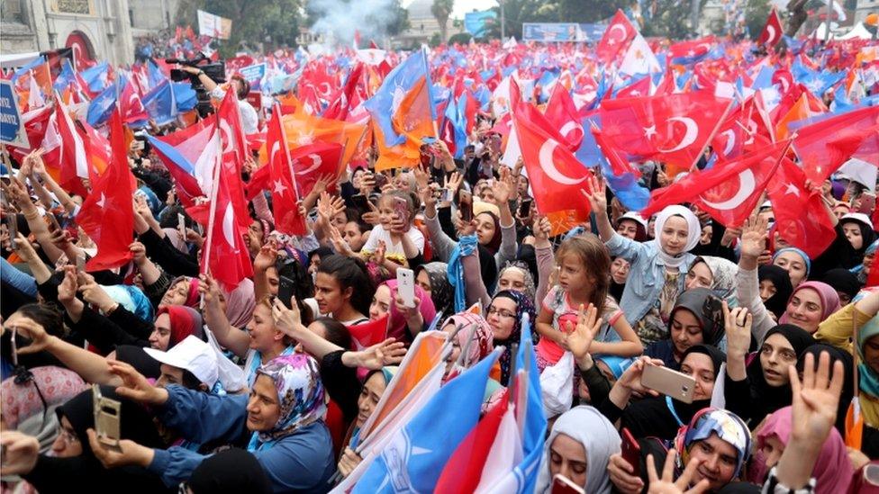 A dense crowd cheer and wave flags at a pro-Erdogan rally