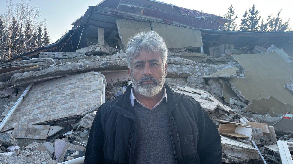 Siho Yukselir, a lorry driver from London stands outside the wreckage of his family's house