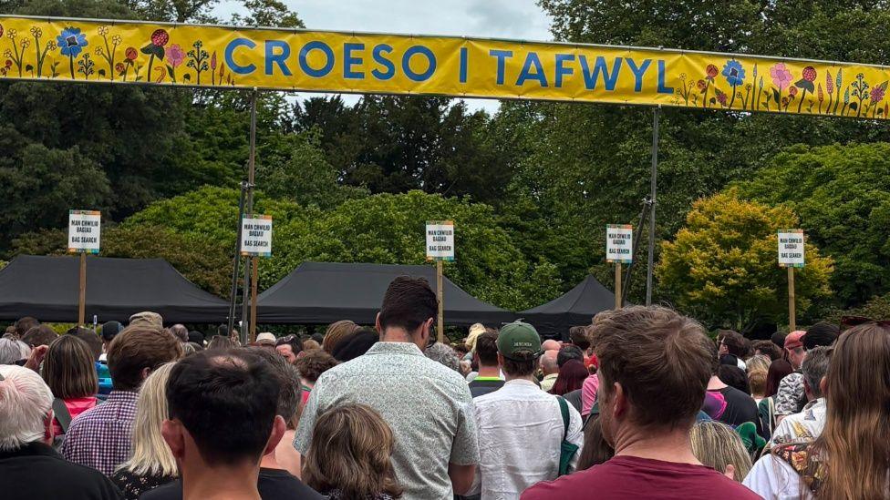 Cefn pennau nifer fawr o bobl yn ciwio i gael mynedfa i ŵyl Tafwyl yng Nghaerdydd ddydd Sadwrn