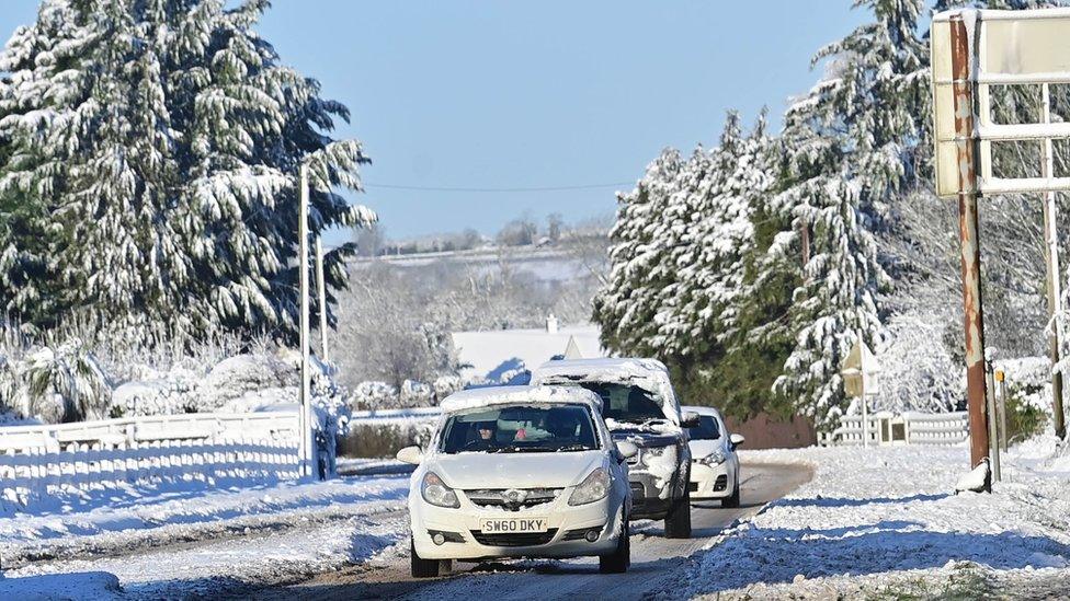 Cars travel along a snow-covered road