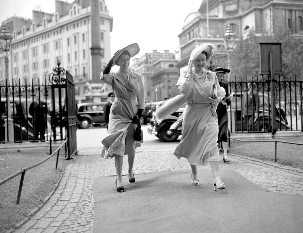 Queen Elizabeth and Princess Elizabeth hold on to their hats as they arrive at Westminster Abbey to attend the wedding of Lady Caroline Montagu-Douglas-Scott to Mr Ian Hedworth Gilmour