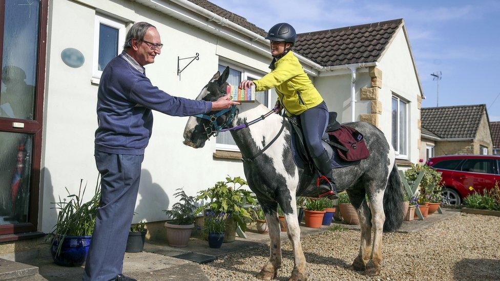 Rescue pony Micky helps owner Abi Eliot-Williams deliver library books to Mike Scott, a member of the Hullavington Book Group in the village of Hullavington near Malmesbry, Wiltshire.