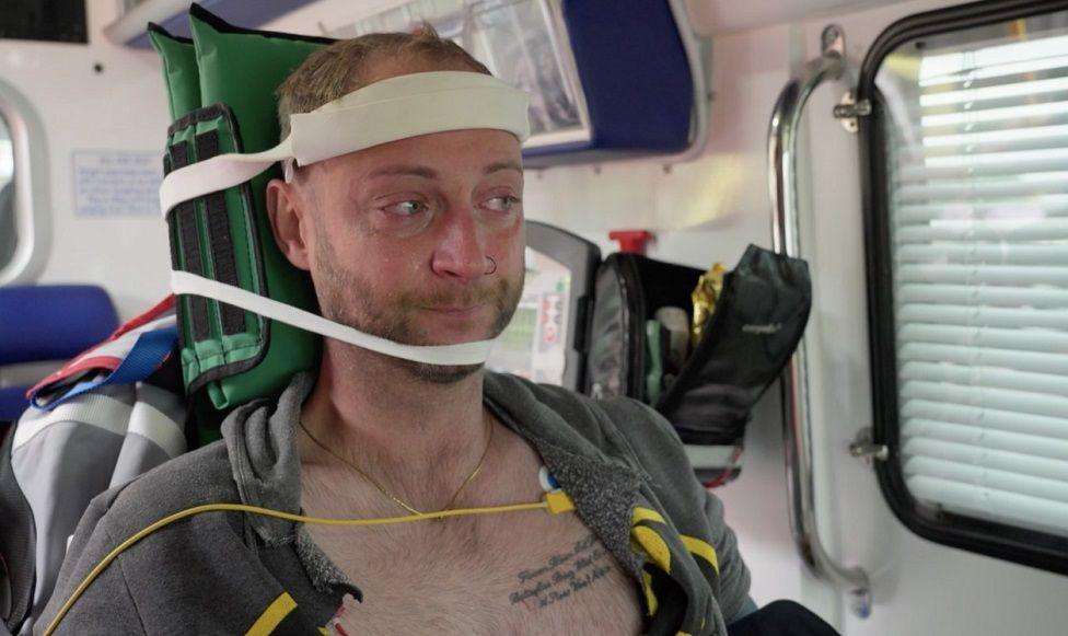 Joe Billingham looking emotional while being strapped up in an ambulance