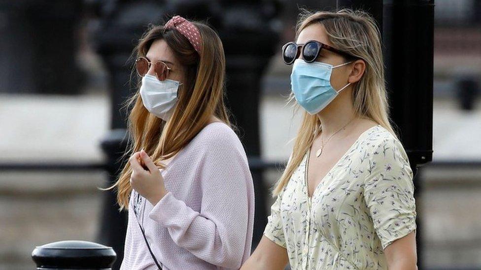 Two women walking wearing face masks